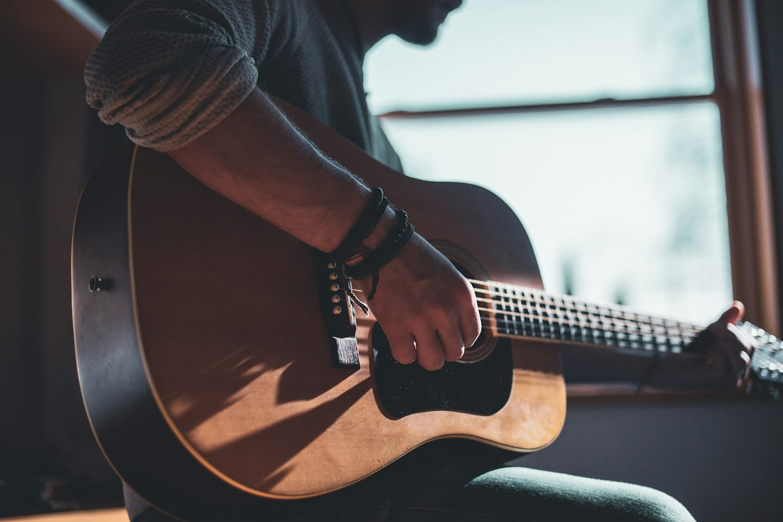 Musicien jouant de la guitare acoustique pour écrire une chanson d'amour à son conjoint